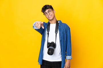 Young photographer man over isolated yellow background pointing front with happy expression