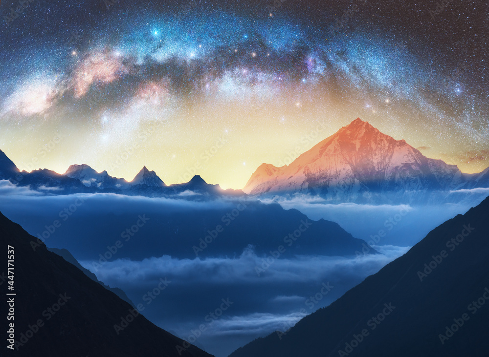 Wall mural milky way arch and snowy mountains in low clouds at starry night. landscape. sky with stars, arched 