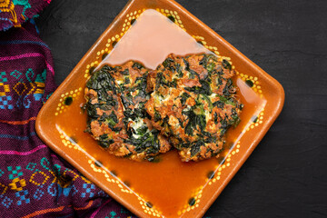 Spinach patties with tomato broth on a dark background. Vegan food