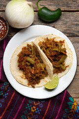Mexican food. Chilorio and nopales tacos on wooden background