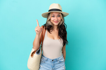 Teenager Russian girl with pamel and beach bag isolated on blue background pointing with the index finger a great idea