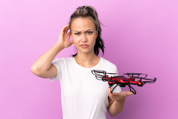 Teenager Russian girl holding a drone isolated on purple background having doubts