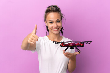 Teenager Russian girl holding a drone isolated on purple background with thumbs up because...