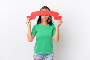 Teenager Russian girl isolated on blue background holding an empty placard and hiding behind it