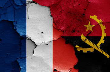 flags of France and Angola painted on cracked wall