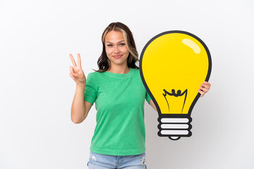 Teenager Russian girl isolated on blue background holding a bulb icon and celebrating a victory