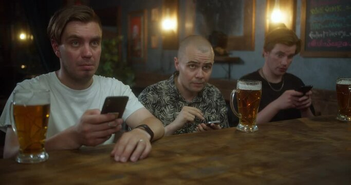 Anxious man checking bets on cellphone, watching sports in bar, bookmaker app