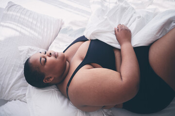 young, plus size woman sleeping peacefully in bed in the morning