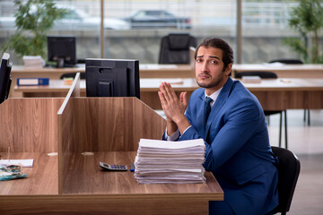 Fototapeta premium Young male employee unhappy with excessive work in the office