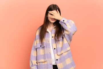 Young Ukrainian girl isolated on pink background covering eyes by hands and smiling