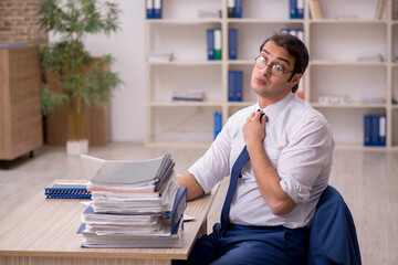 Young male employee and a lot of work in the office