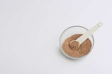 Linseed powder in transparent copper bowl with white background. Natural aphrodisiac. Healthy living concept