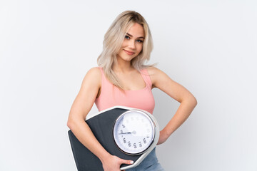 Teenager girl over isolated white background with arms at hip and holding weighing machine