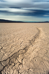 dry cracked earth in the desert and mountains background blue sky
