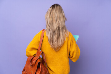 Teenager Russian student girl isolated on purple background in back position