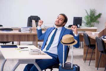 Young male employee preparing for trip in the office