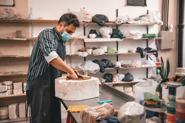 young adult potter molding with clay to make a piece of ceramic