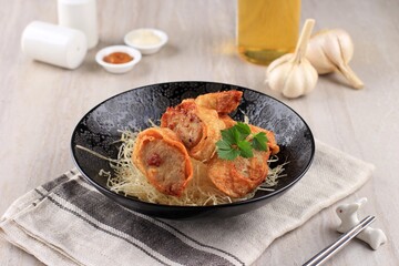 Slices of Chicken Egg Rolls, is Omelete Egg Stuffed with Ground Chicken and Spices, Steamed and Deep Fry, Served with Chili Mayonaise Sauce Above Crispy Vermicelli
