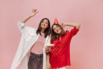 Happy good-humored women in oversized stylish shirts smile and celebrate birthday on pink isolated...