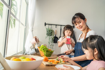 Asian beautiful mother cooking vegetable salad with two young daughter