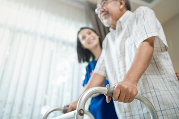 Close up of nurse help disable man walk with walker at nursing home. 
