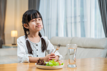 Obraz na płótnie Canvas Asian little girl child eat green vegetable in plate on dinner table. 
