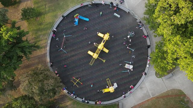 Aerial top down view of children enjoying swings and slides in the outdoor park.