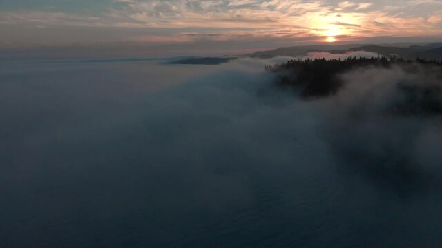 Aerial time lapse of a bank of sea fog moving down a bay over a the rugged Vancouver Island coastline. - 4K 24FPS