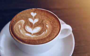 Close up of a cup of hot latte coffee on wooden table. A latte is a coffee drink made with espresso and steamed milk.