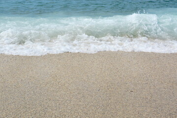 sea coast concept. sea sand and surf with white foam from blue wave with copy space on sand