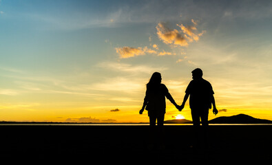 Fototapeta na wymiar silhouette of couple holding hands in field at sunset