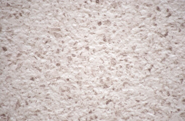 Roughly finished surface of pink stone with small red blotches.