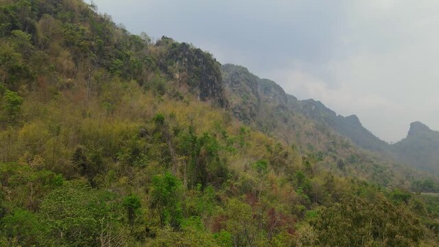 Aerial dolly in footage featuring astonishing view of jungle growing on very steep slope of limestone mountain that took millennium of years to form In Thailand, Asia.