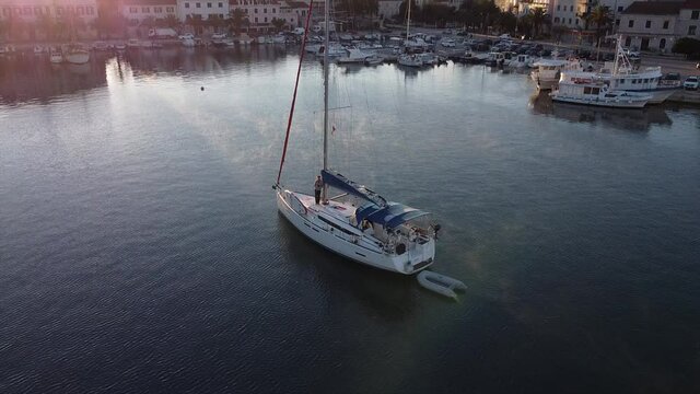 Drone doing a skyrocket movement over sailboat laying in harbour with end camera movement point downward
