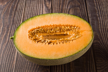 close-up of cut fresh Hami melon fruit on wooden background.