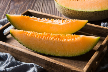 close-up of cut fresh Hami melon fruit on wooden background.