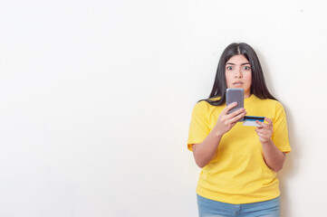 young white latin girl with black hair wearing yellow dress caught making an online transaction with her phone and card