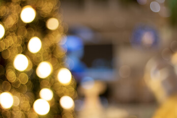 Yellow christmas tree bokeh background of de focused glittering lights in the mall.