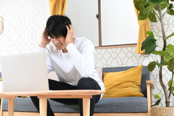 パソコンの前で頭を抱える若い男性