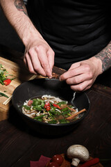 Chef adding spices while cooking asian dish