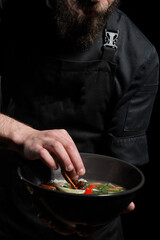 Chef adding spices while cooking asian dish