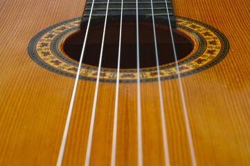 Closeup of the strings of a brown acoustic guitar