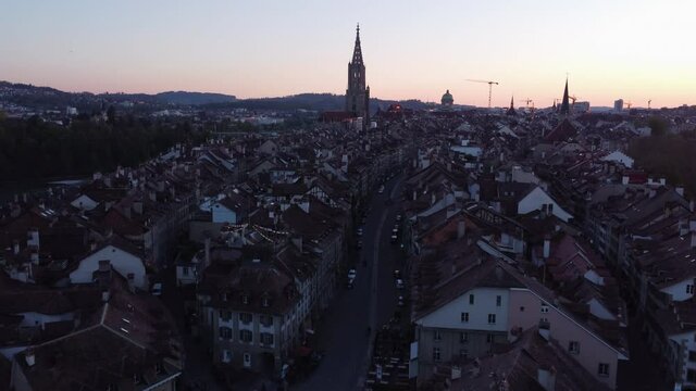 Slow aerial shot of buildings and a large cathedral in Bern, Switzerland at sunset.