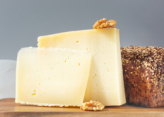 Pieces of asiago cheese, walnut and bread on kitchen wooden board