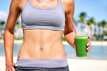 Green juice smoothie healthy detox diet weight loss fit woman drinking juice on outdoor beach...