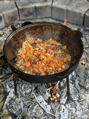 gourmet beef stew cooked in cauldron on outdoor fire pit