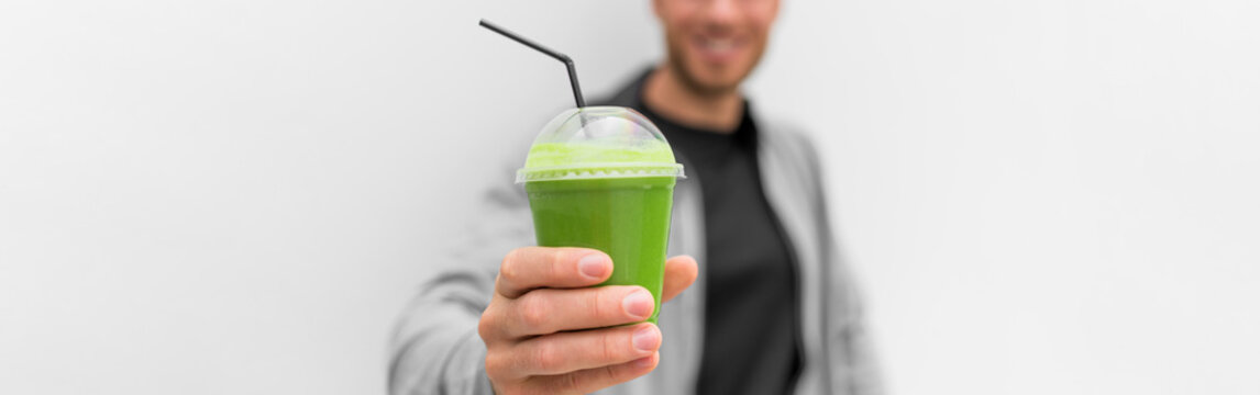 Green Smoothie Juice Drink At Cafe Banner. Healthy Man Drinking Detox Diet Protein Shake White Background Panoramic. Hand Holding Plastic Cup Of Vegetable Juice, Health Food Eating Lifestyle.