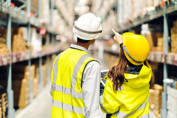 Asian two engineer in helmet team order detail on tablet computer for checking goods and supplies on shelves with goods background in warehouse.logistic and business export