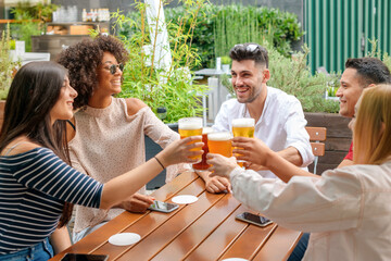 Group of friends celebrating at an open air restaurant - obrazy, fototapety, plakaty