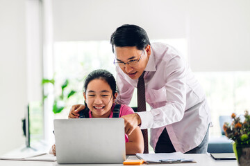 Father and asian kid little girl learning and looking at laptop computer making homework studying knowledge with online education e-learning system.children video conference with teacher tutor